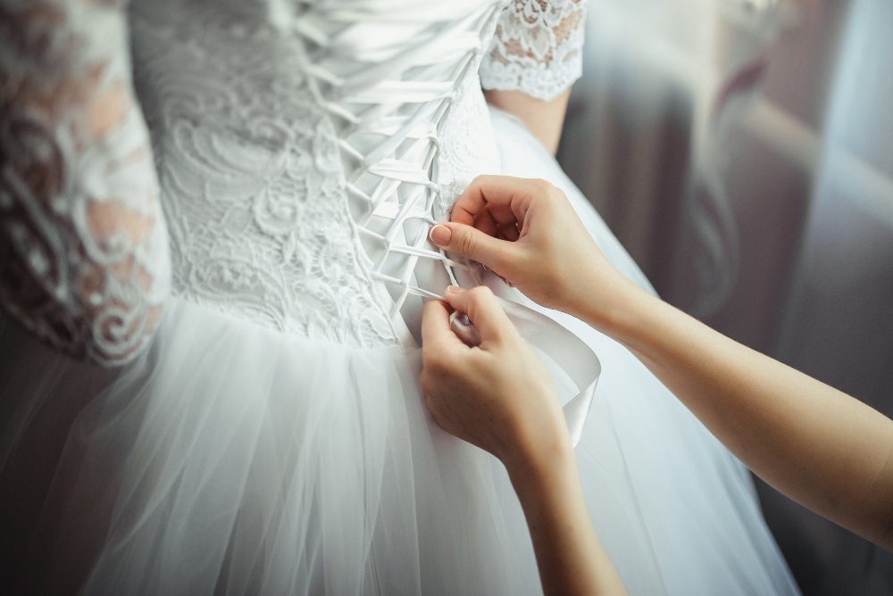 Bridesmaid makes bow-knot on the back of brides wedding dress Bridesmaid makes bow-knot on the back of brides wedding dress<br />